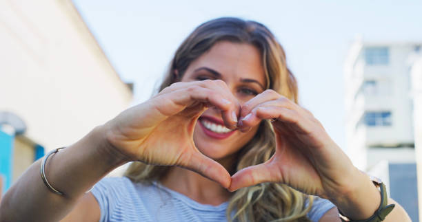 Hands, heart and smile of woman with sign of love, care and empathy in portrait in city, street or urban Australia. Compassion, emoji and face of model with happiness on holiday with support or style